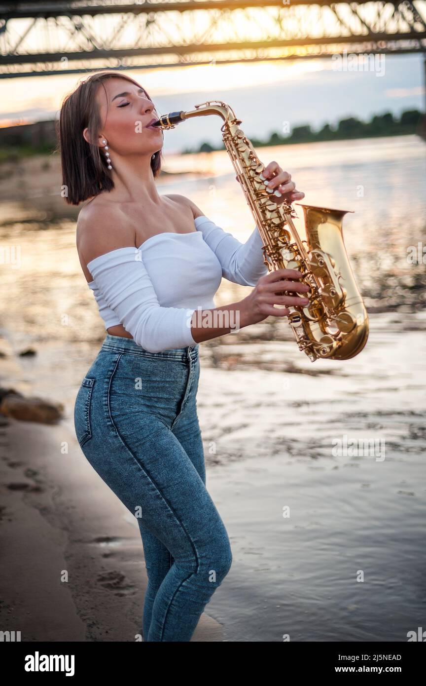 Woman playing the saxophone at sunset Stock Photo