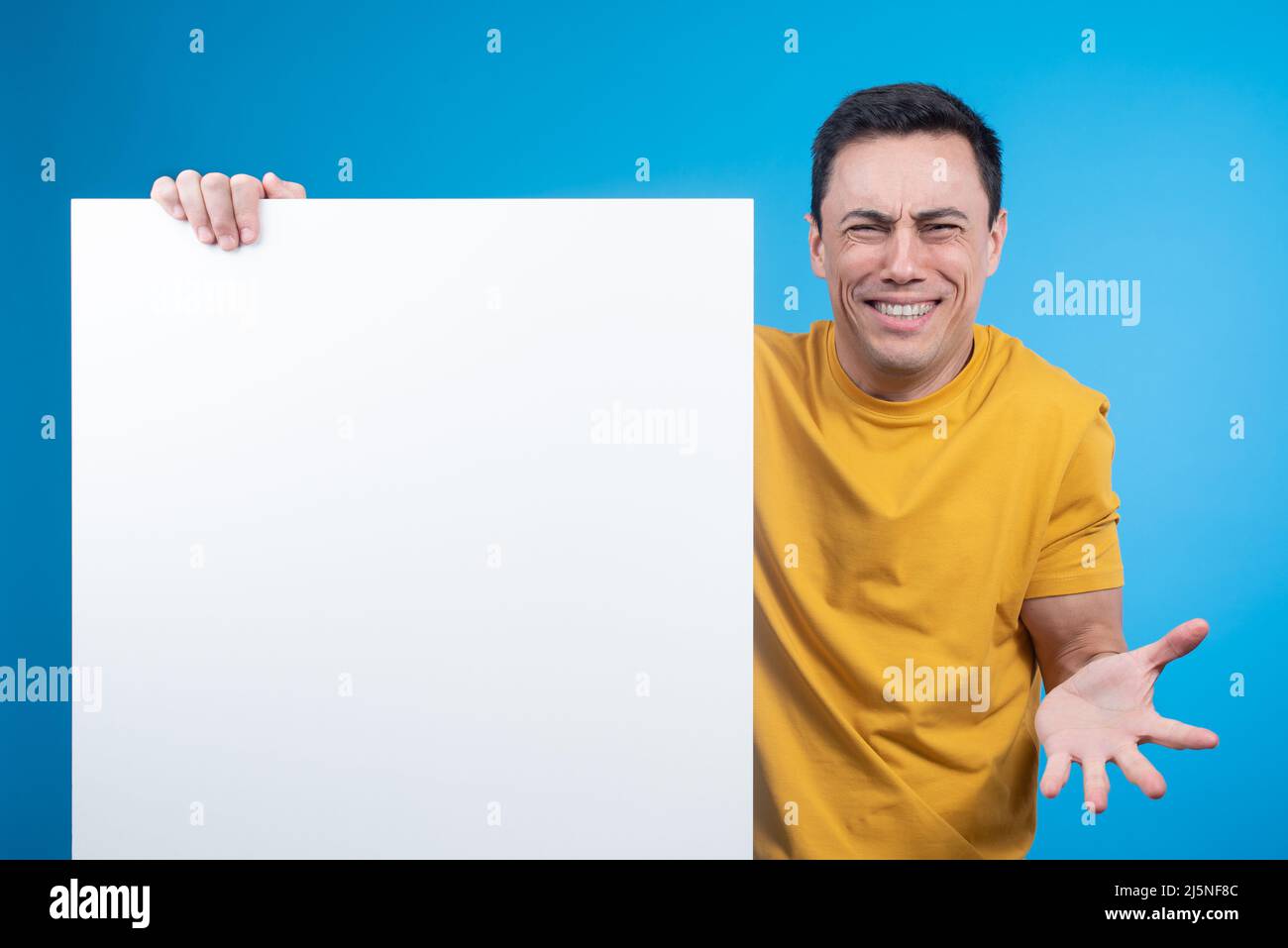 Confused smiling man demonstrating blank banner for advert Stock Photo