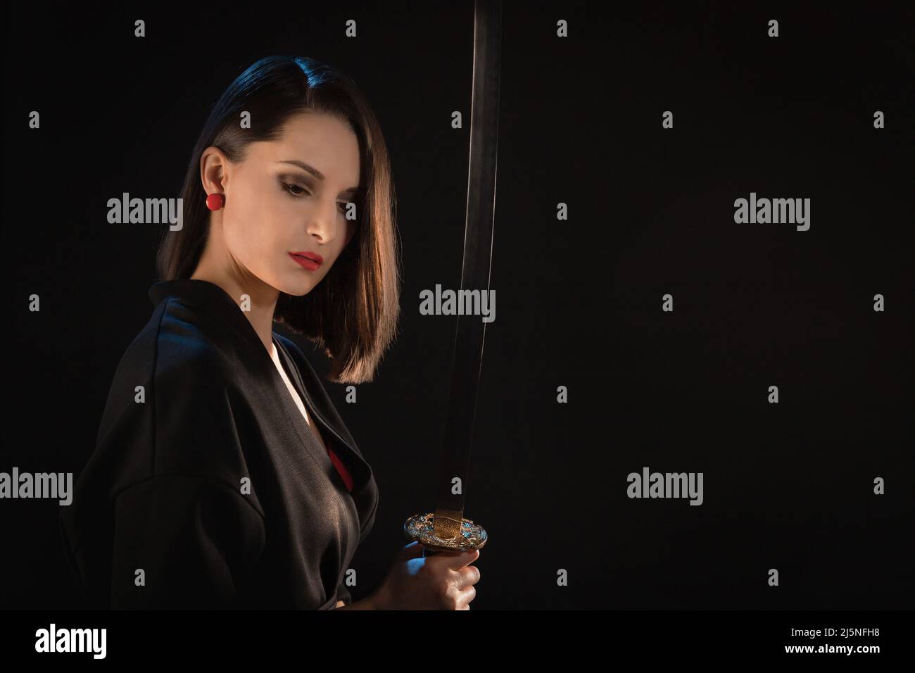 Portrait of a pensive young warrior woman with an Asian sword. Stock Photo