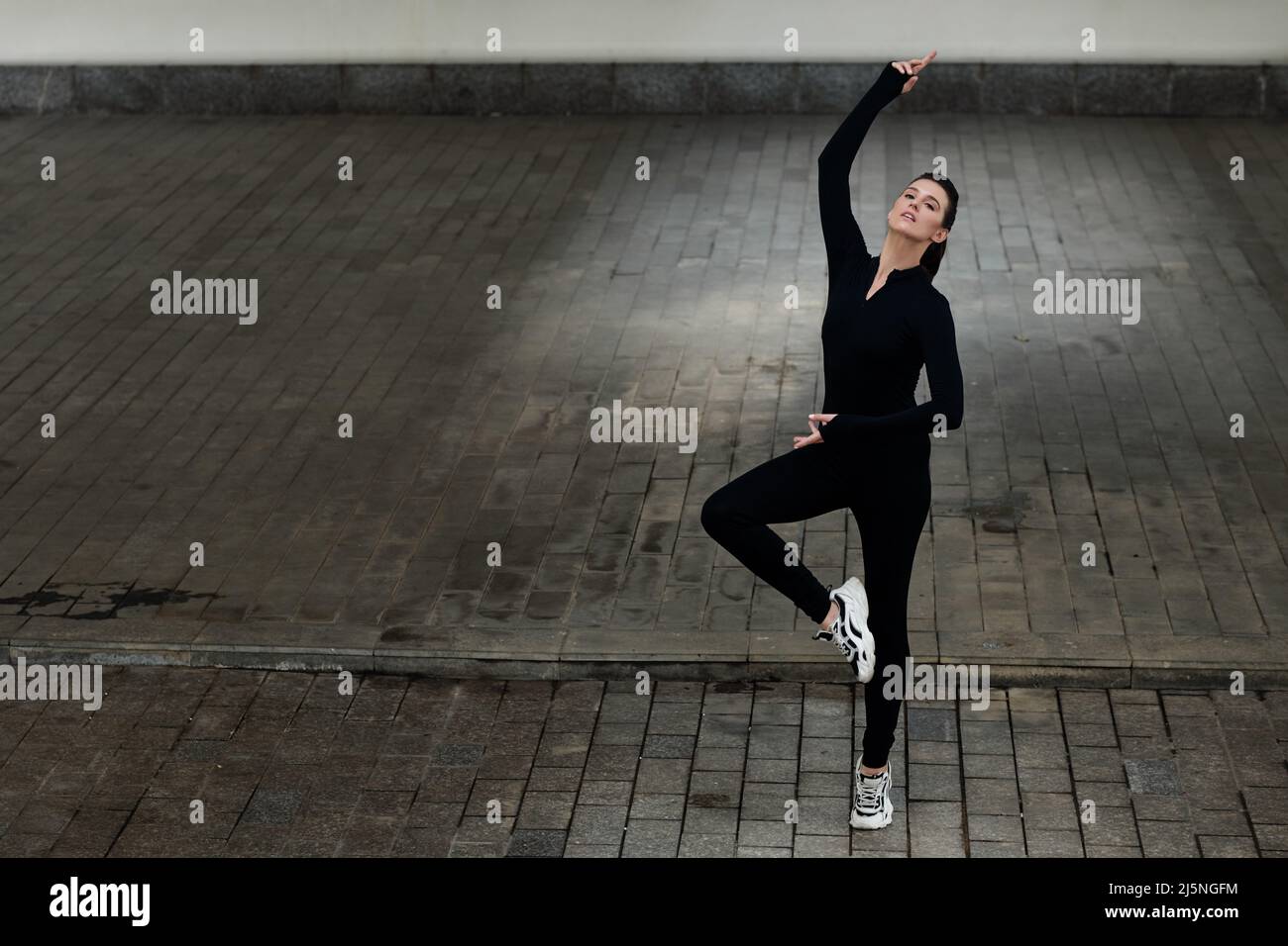Young female dancer in black unitard enjoying performaning outdoors Stock Photo
