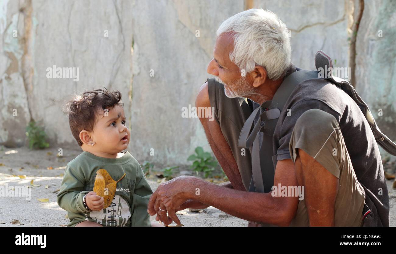 Pali, Rajasthan India -March17,2022.Close-up Photo of a newborn indian baby looking at the grandfather with holding autumn leaf Stock Photo