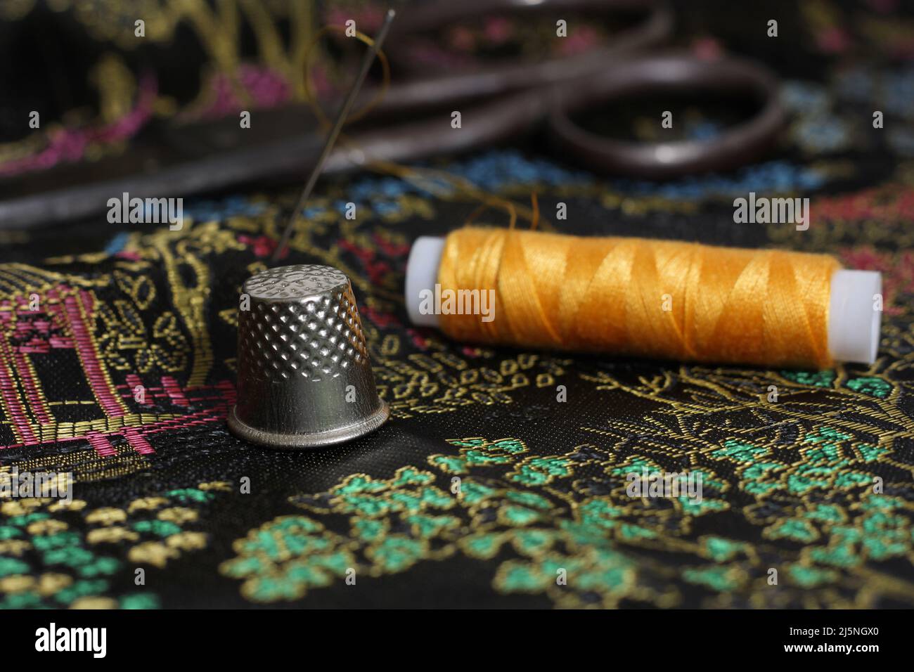 Yellow Thread and Thimble on Vintage Chinese Silk Stock Photo