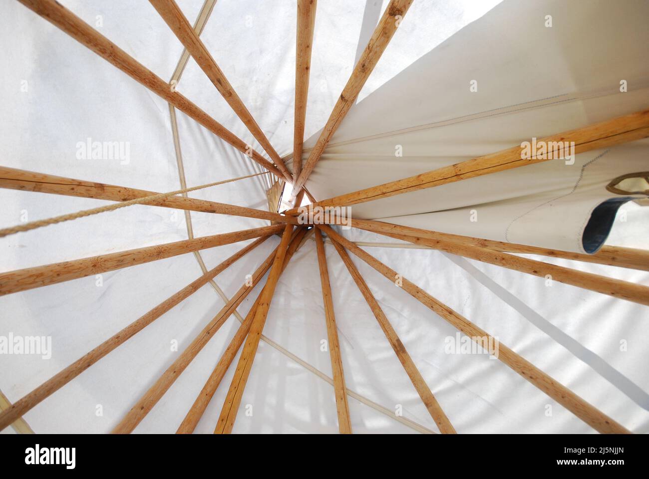 Indoor view of top of tipi with poles and white fabric at campsite Stock Photo