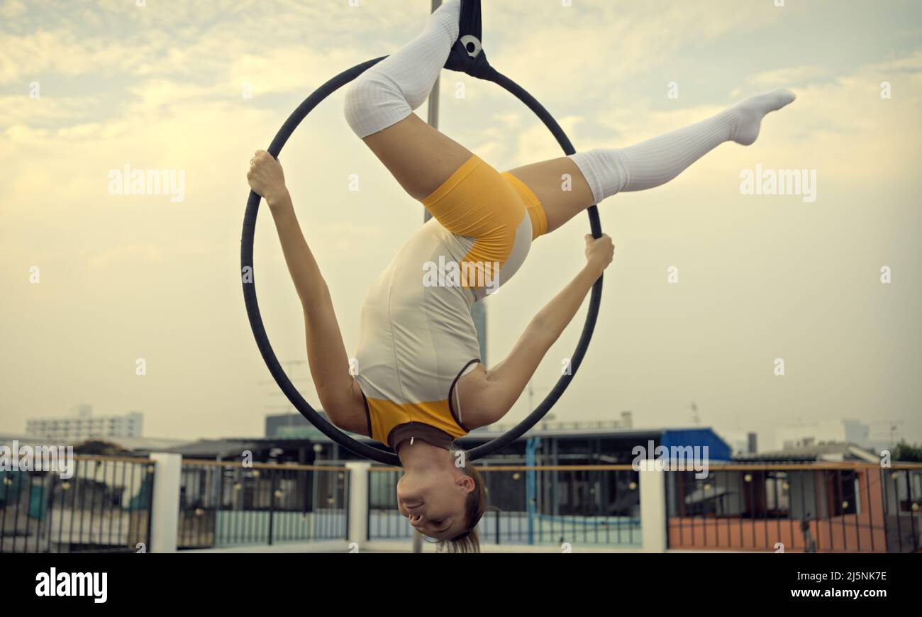 Woman in sportswear doing sky yoga on the rooftop in the evening when the sun set. Self care and health concepts. Stock Photo