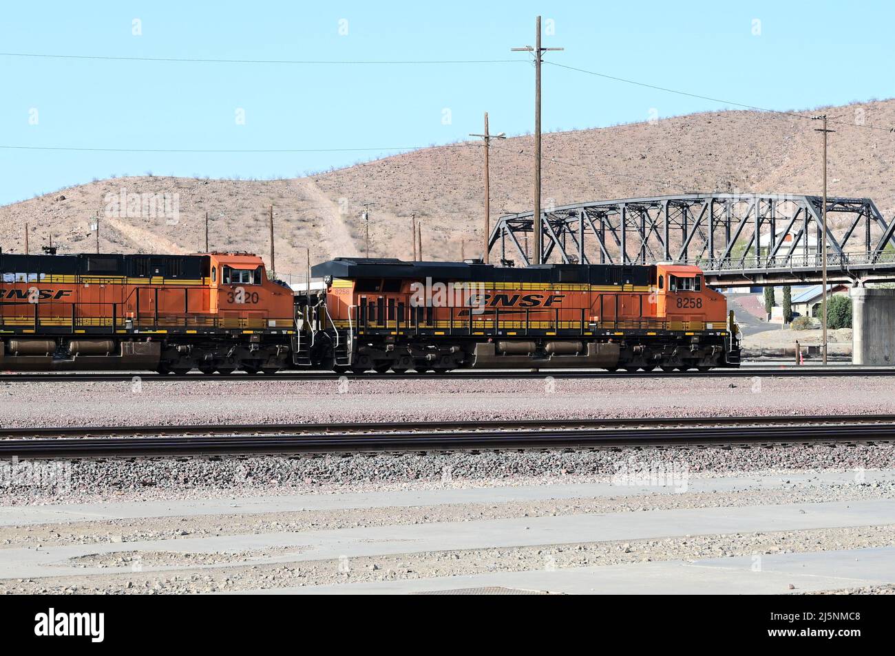 BNSF 7780 BNSF Railway GE ES44DC locomotive passing through Barstow station with a freight train. Stock Photo