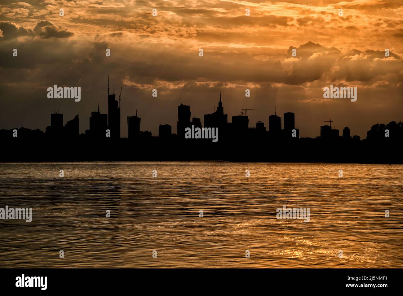 Warsaw skyline at sunset, golden light in sky and river and downtown ...