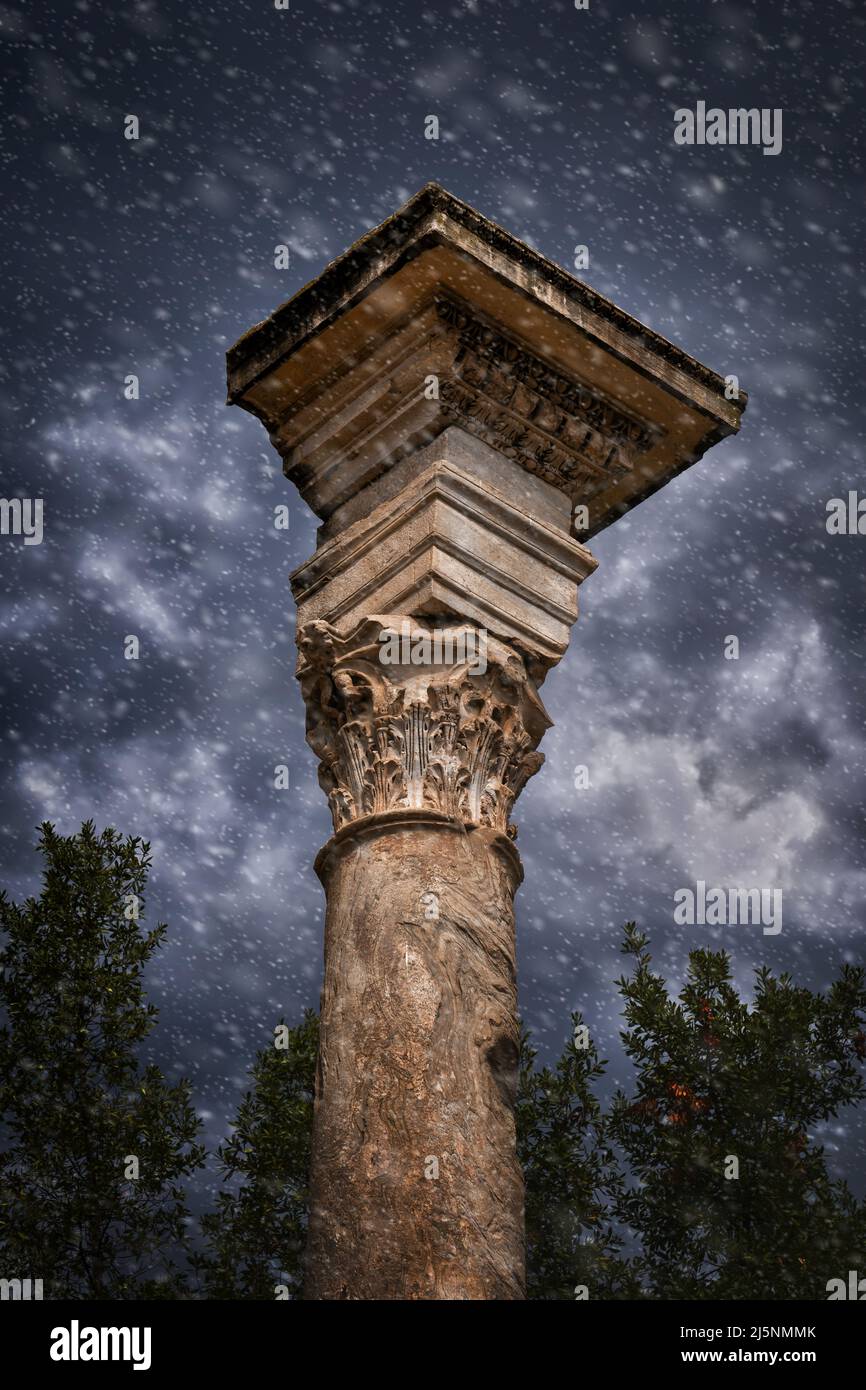 Snowfall at ancient Corinthian column against stormy sky at the Roman Forum in Rome, Italy. The column can be found next to the Temple of Romulus. Stock Photo