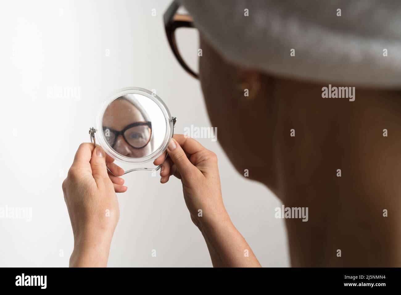 Middle age caucasian woman after bath looking in her mirror reflection. Daily routine of facial treatment  Stock Photo