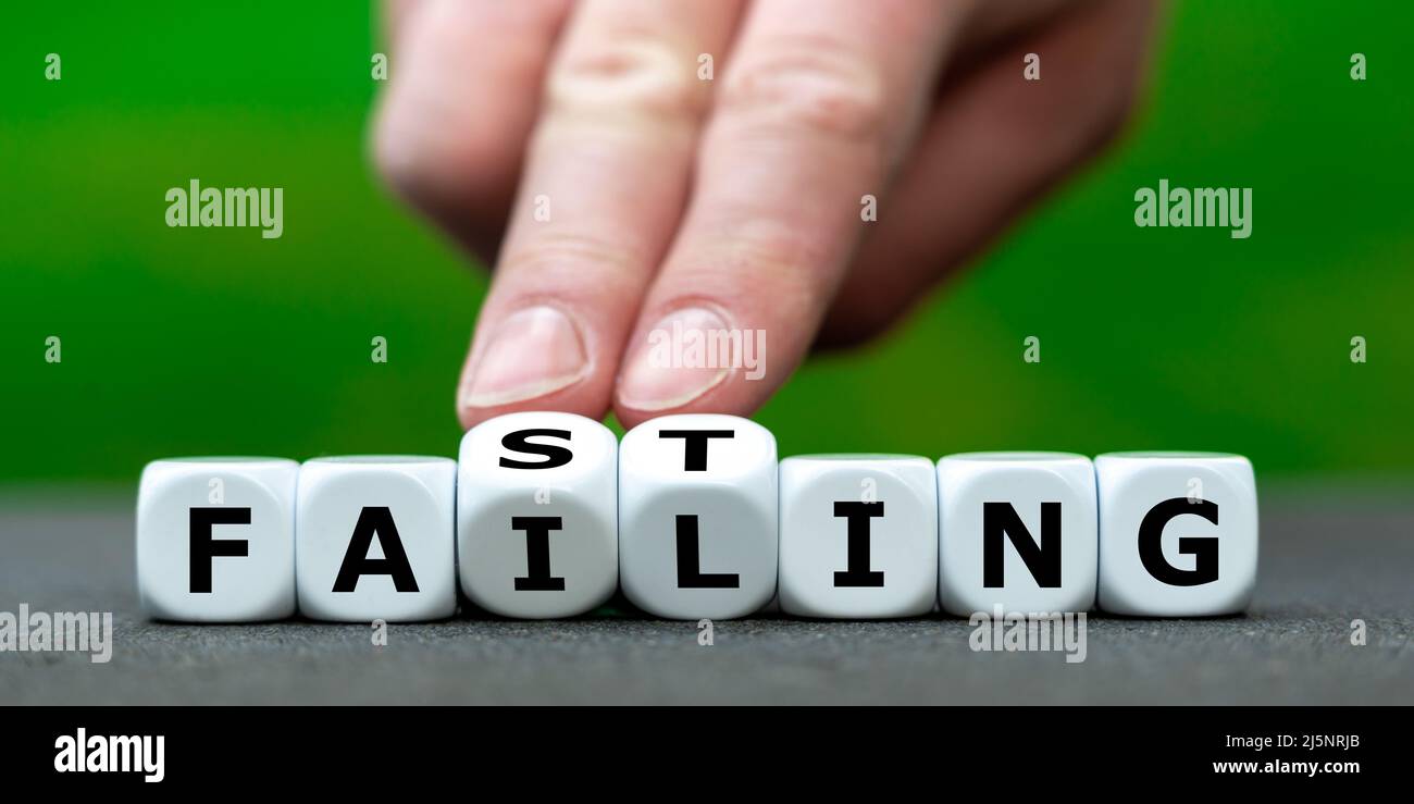 Hand turns dice and changes the expression 'failing' to Fasting'. Stock Photo