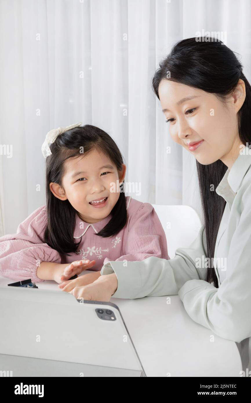 Asian Korean mother and daughter taking online classes on tablet Stock