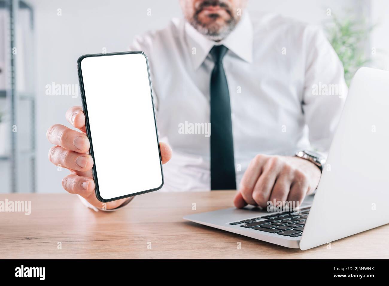 Mobile smart phone mock up screen, businessman holding cellular phone with blank white display in office, selective focus Stock Photo