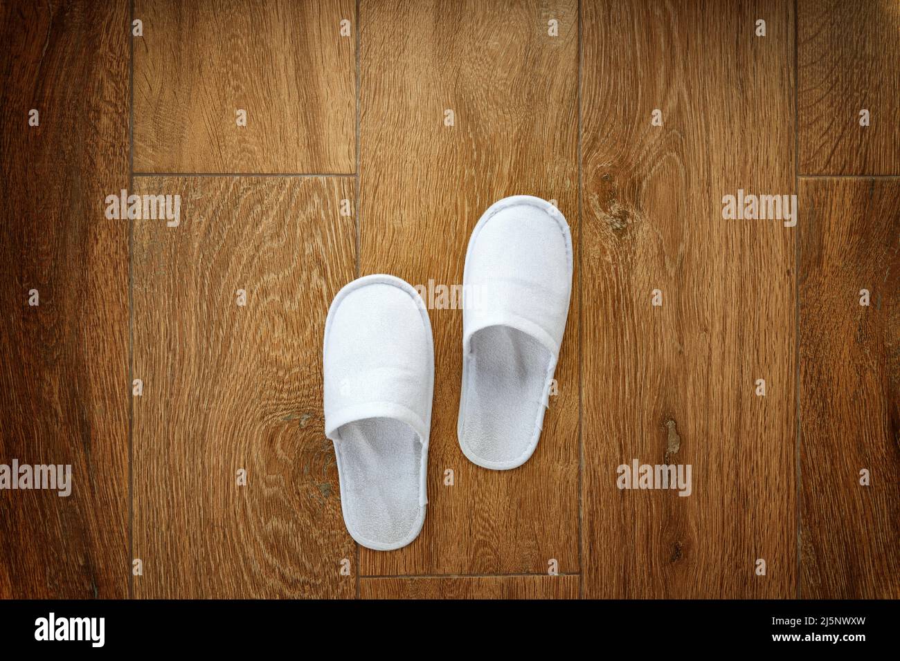 Disposable white slippers on hotel room floor, top view Stock Photo