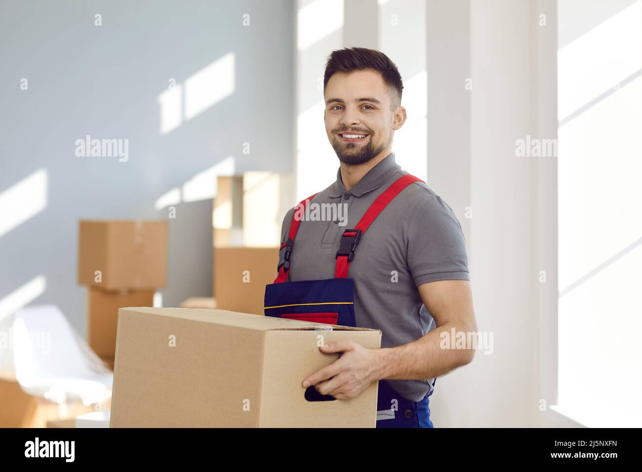 Happy delivery service or moving company worker holding cardboard box and smiling Stock Photo