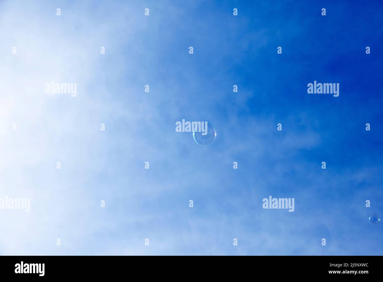 a soap bubble against a blue sky with thin clouds Stock Photo - Alamy