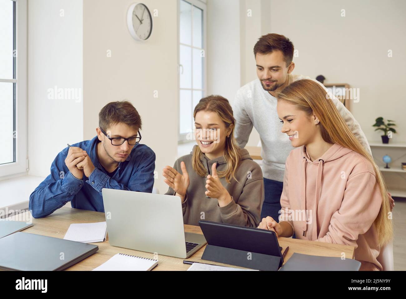 Happy university students using laptop and tablet while working on group project Stock Photo