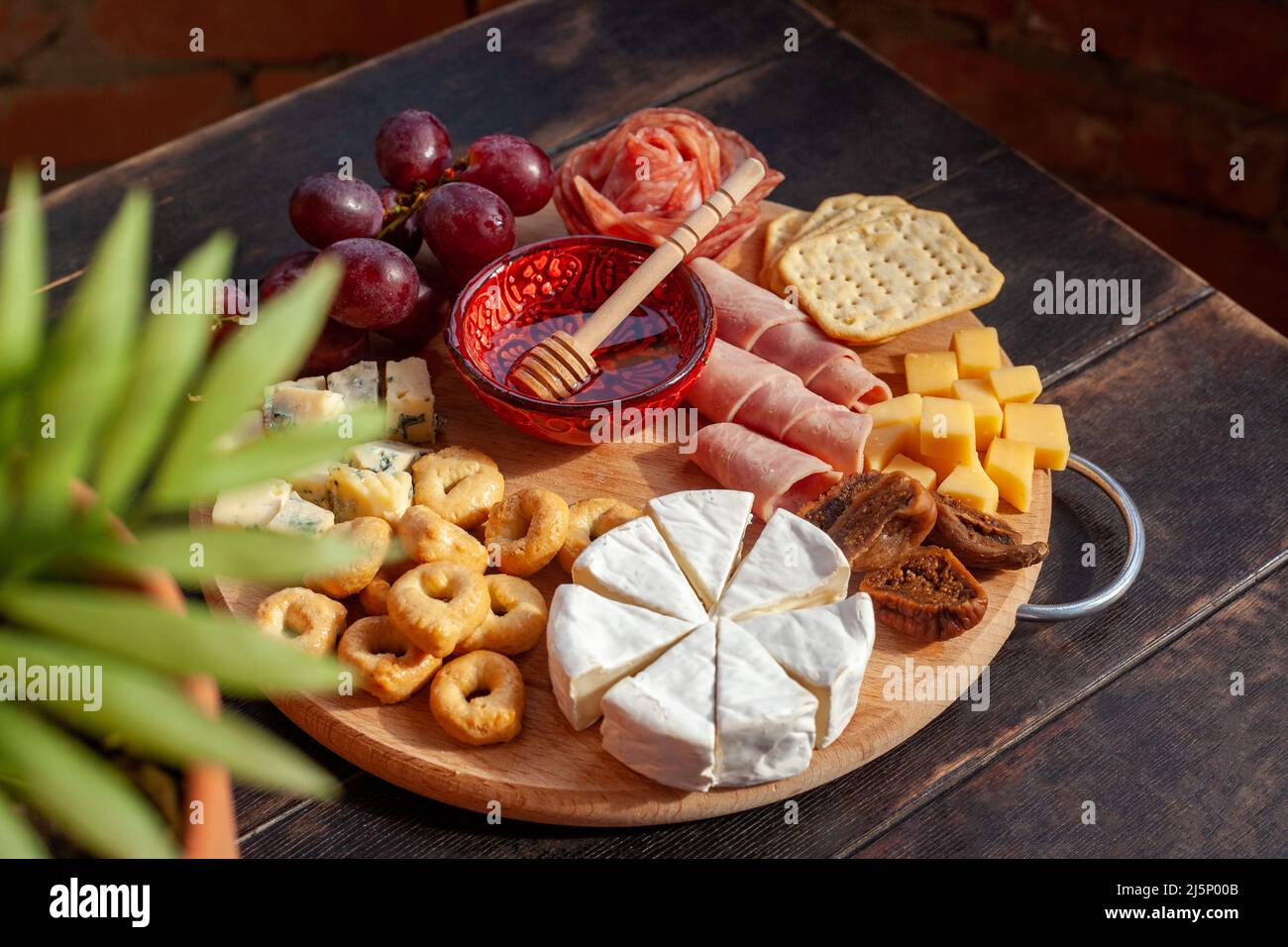 Round cutting board with slicing assorted cheese, sausage rosette, ham