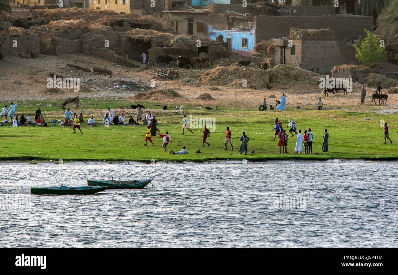 Men and boys play a game of football on the bank of the River Nile at Esna in Egypt in the late afternoon. Stock Photo