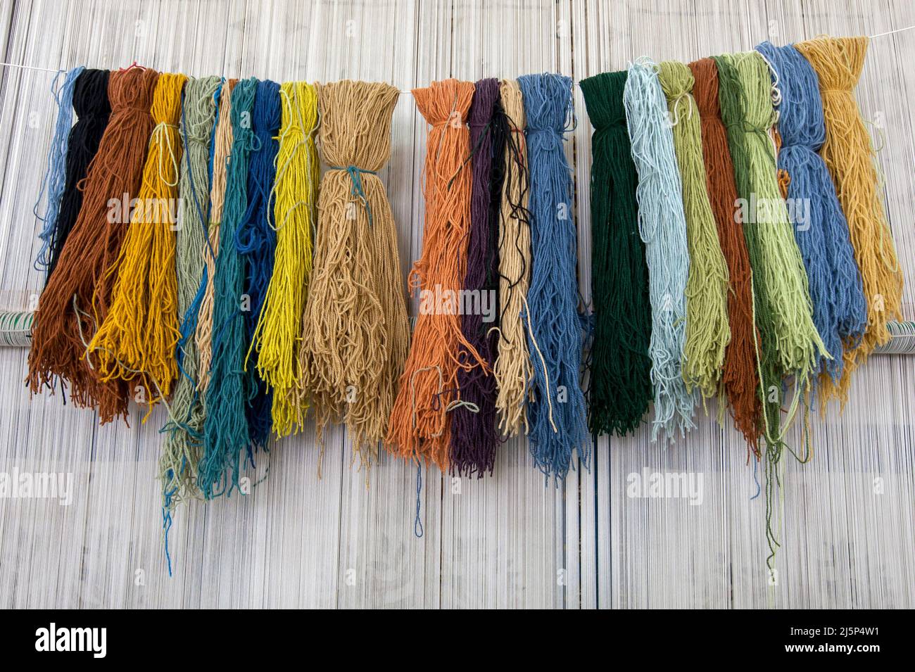 A variety of colourful woollen threads hang ready to be used in the making of an Egyptian carpet at a textile factory in Cairo, Egypt. Stock Photo