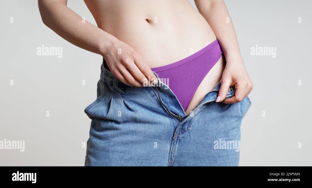 woman in open jeans undressing showing purple panties Stock Photo