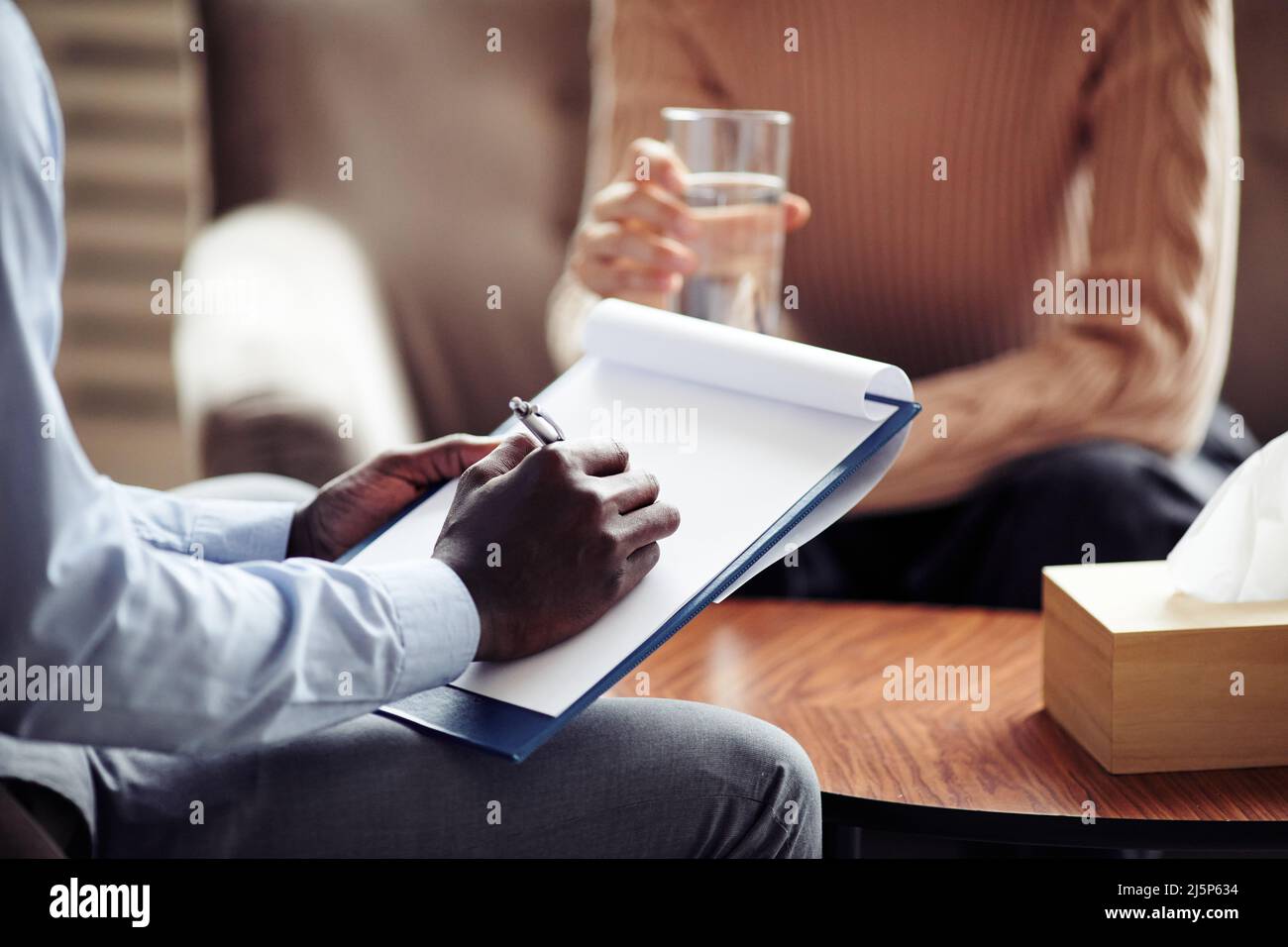 Closeup image of psychiatrist taking notes during therapy session with