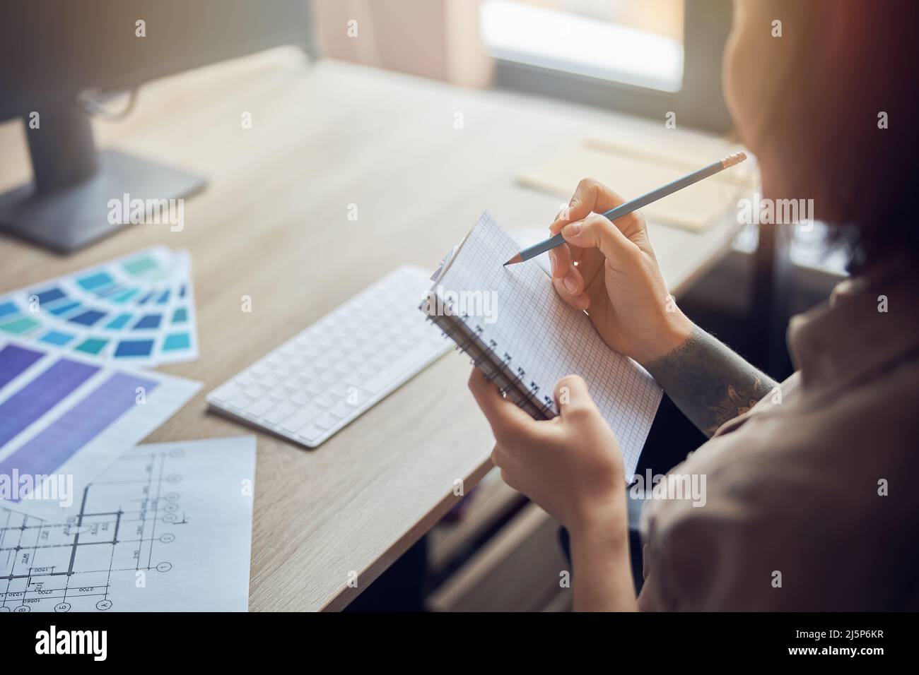 Close up of female interior designer making notes in her notebook while ...