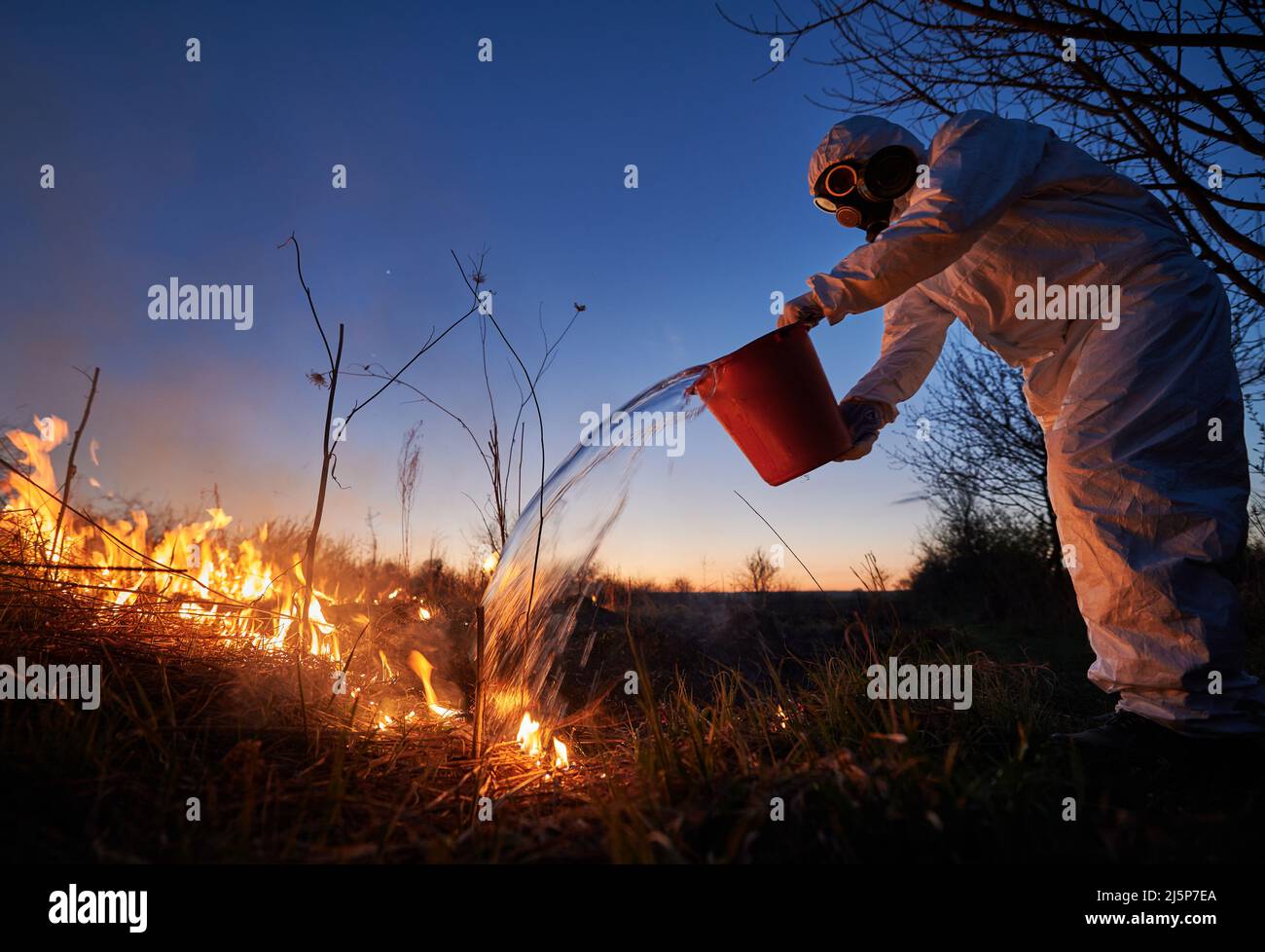 Research scientist fighting fire in field with blue night sky on