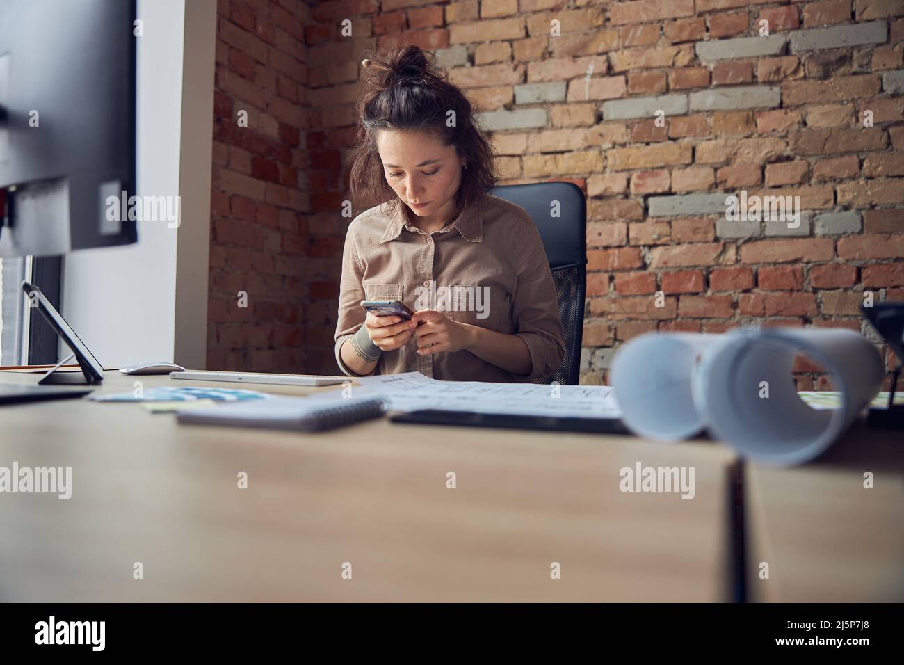 Female interior designer using smartphone while working in her office Stock Photo