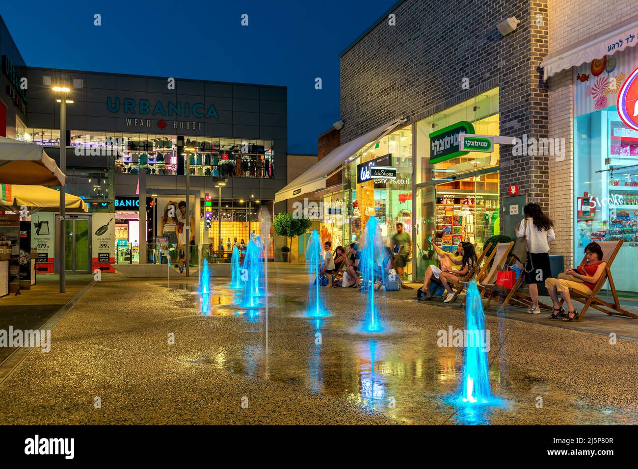 Shops, retail stores and illuminated fountains in open air mall at evening in Ashdod, Israel. Stock Photo