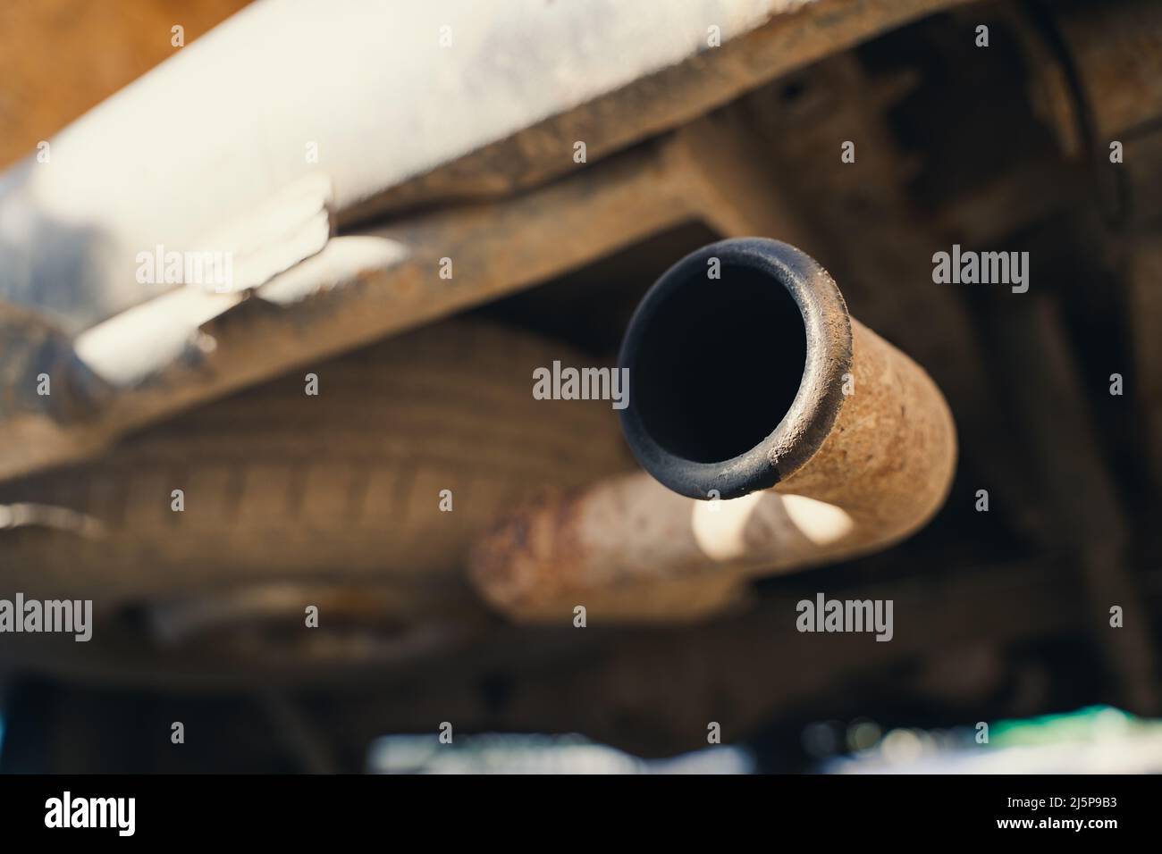 Rusty exhaust pipe with soot closeup. The spare tire is installed from