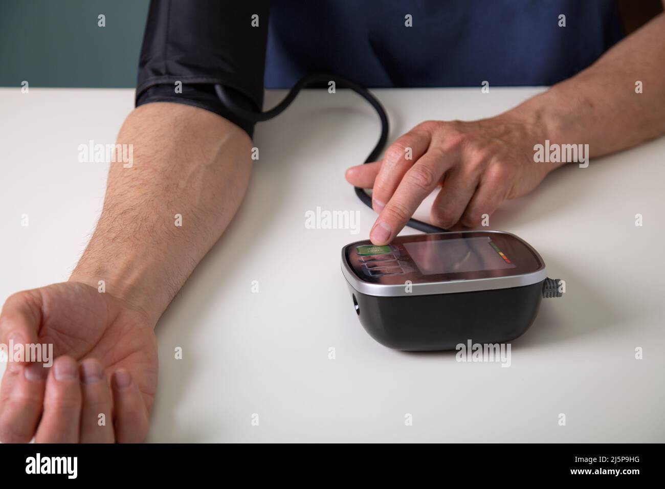 Middle aged man testing his blood pressure at home with a digital blood pressure monitor Stock Photo