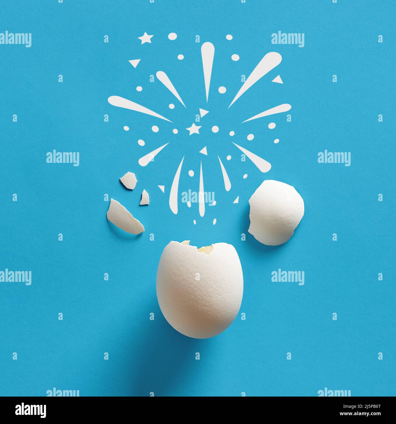 Cracked white chicken egg shell with fireworks symbol. Celebration, birthday, surprise concepts. Stock Photo