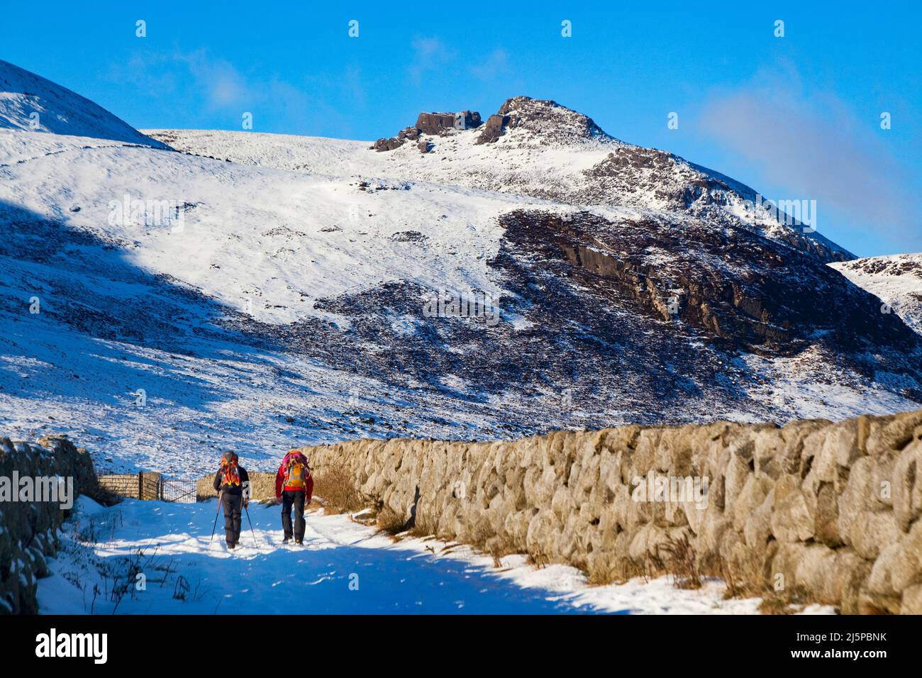 A couple of hikers walking into the Mountains of Mourne in the snow, Newcastle, County Down, Northern Ireland Stock Photo