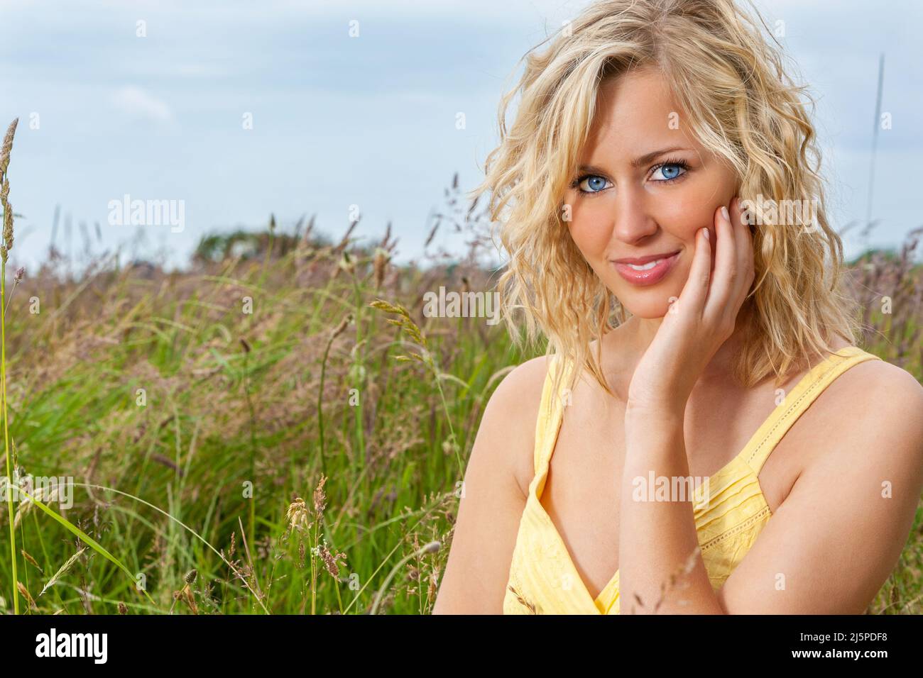 Outdoor smiling happy portrait of smiling and happy, beautiful young female teenager with blonde hair and in a green field Stock Photo