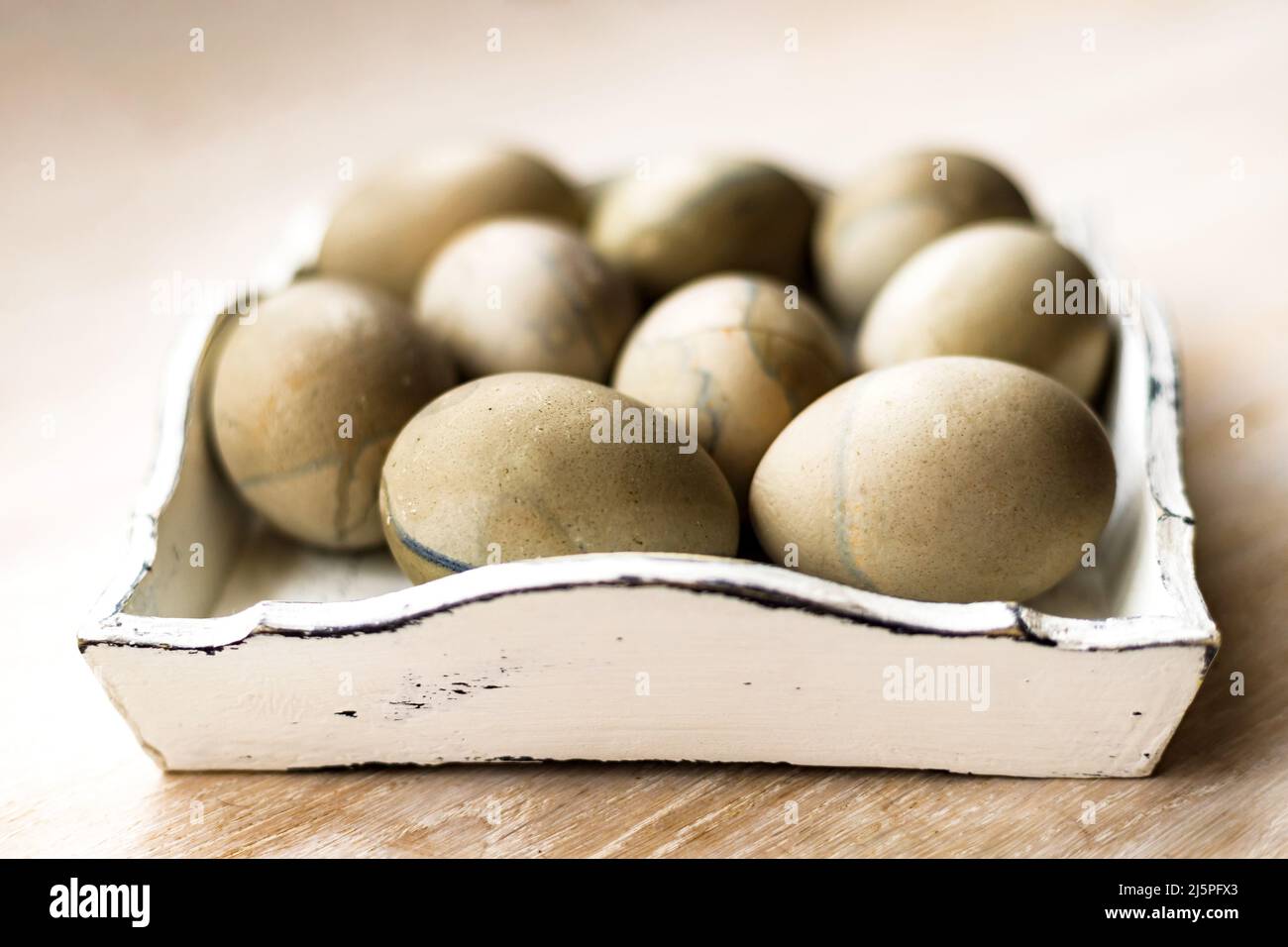 Group of homemade gibiscus painted colored easter eggs on white rustic wooden tray, table background Stock Photo