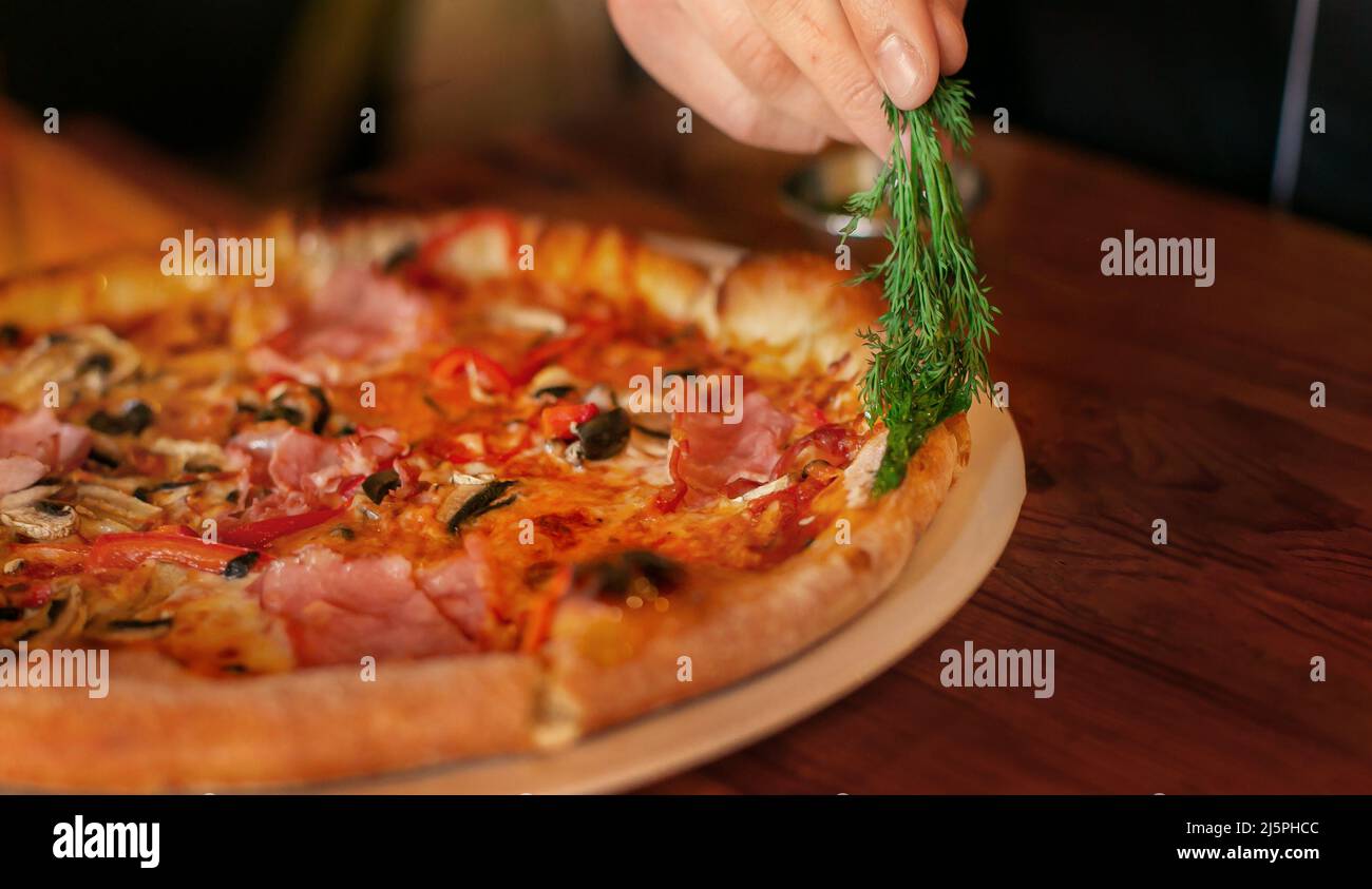 pizza preparation oiling by dill oil ready pizza. male hand Stock Photo