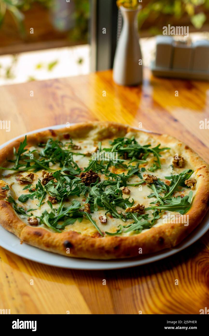 Delicious vegeterian cheese pizza with walnuts and basil wooden table background, closeup. place for text Stock Photo