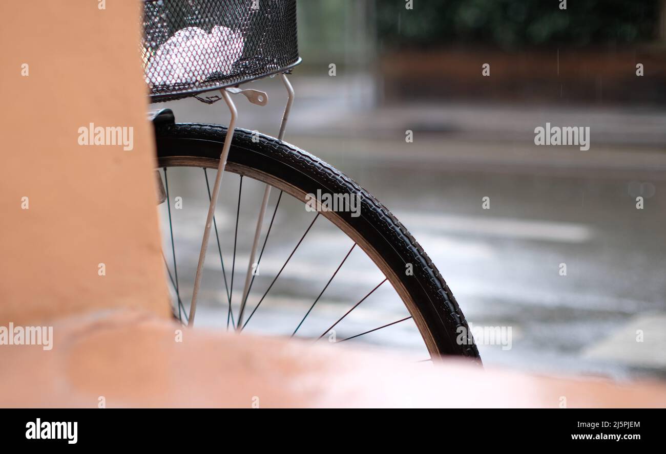 wheel detail of a bike leaning against a porch during a rainy day Stock Photo