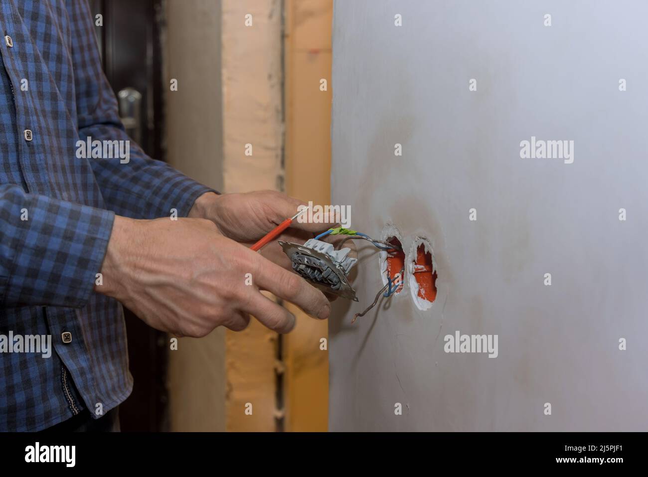 Electrician installing a light switch with a wall Stock Photo