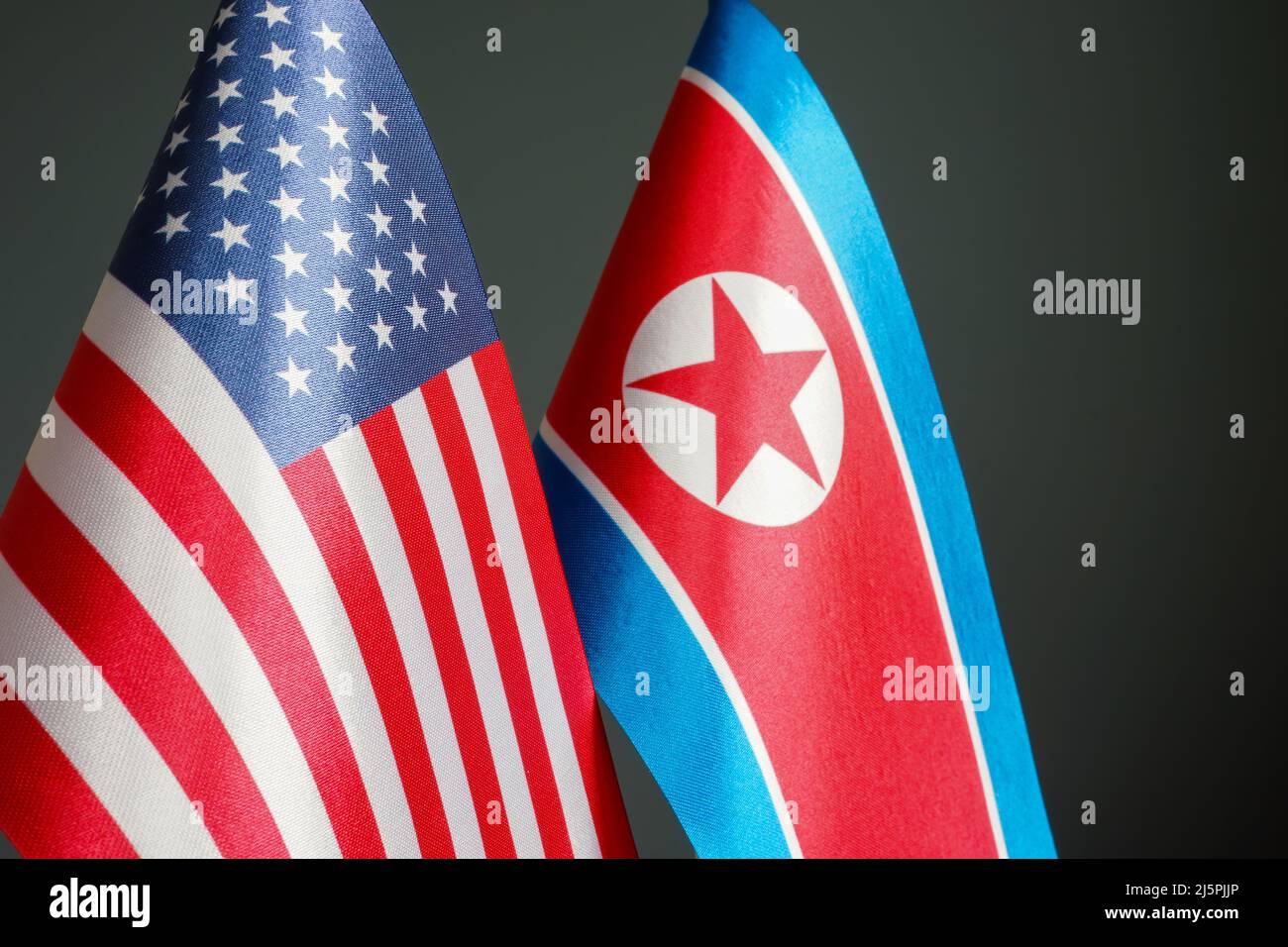 Flags of North Korea and the USA on a dark surface. Stock Photo