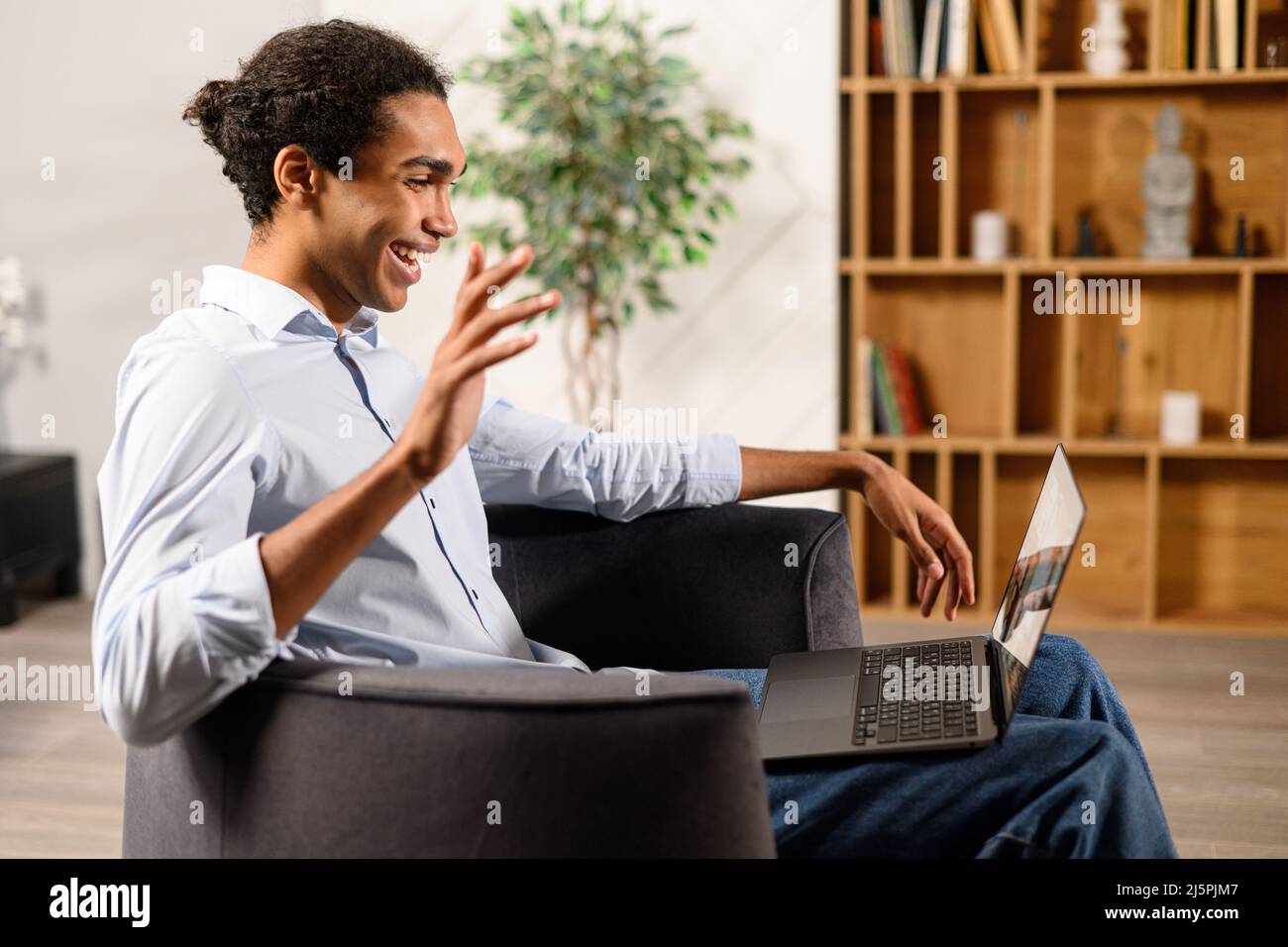 Side view of the multiracial young guy uses a laptop for a video