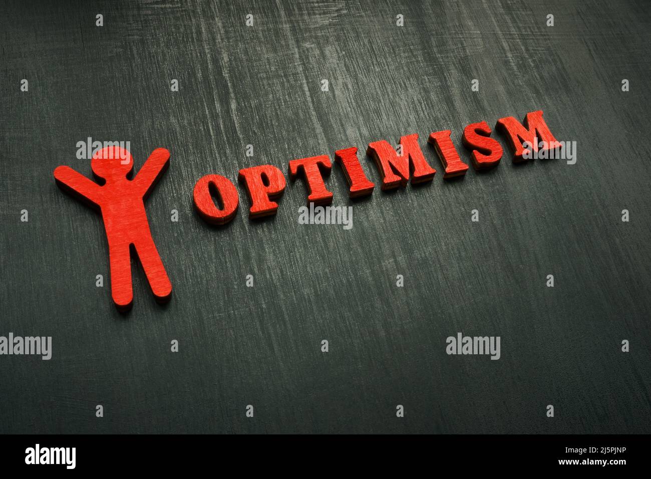 Figurine and word optimism on the dark surface. Stock Photo
