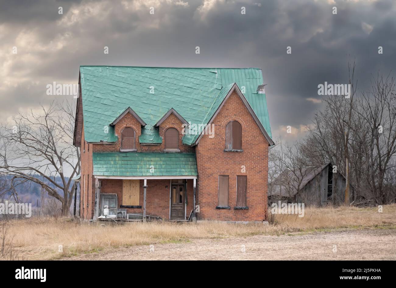 An old abandoned spooky looking farmhouse in winter on a farm yard in rural Canada Stock Photo