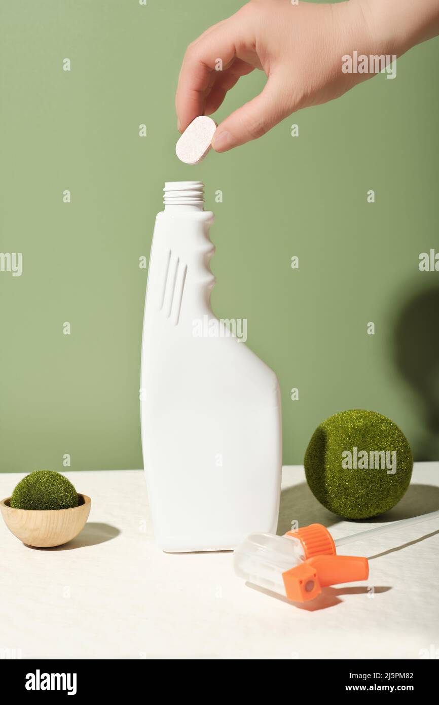 hand holding dissoluble tablet for cleaning detergent refill. bottle of