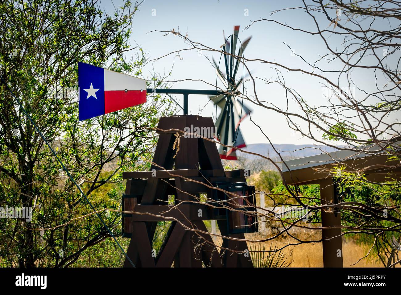 The wind spins the blades of a little windmill that sits aside a highway and painted in the Lonestar flag colors near El Paso, Texas. Stock Photo