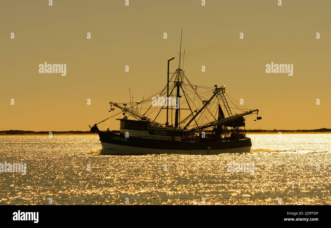 A commercial shrimp boat heads out to see through the Brownsville Ship Channel by South Padre Island, Texas. Stock Photo