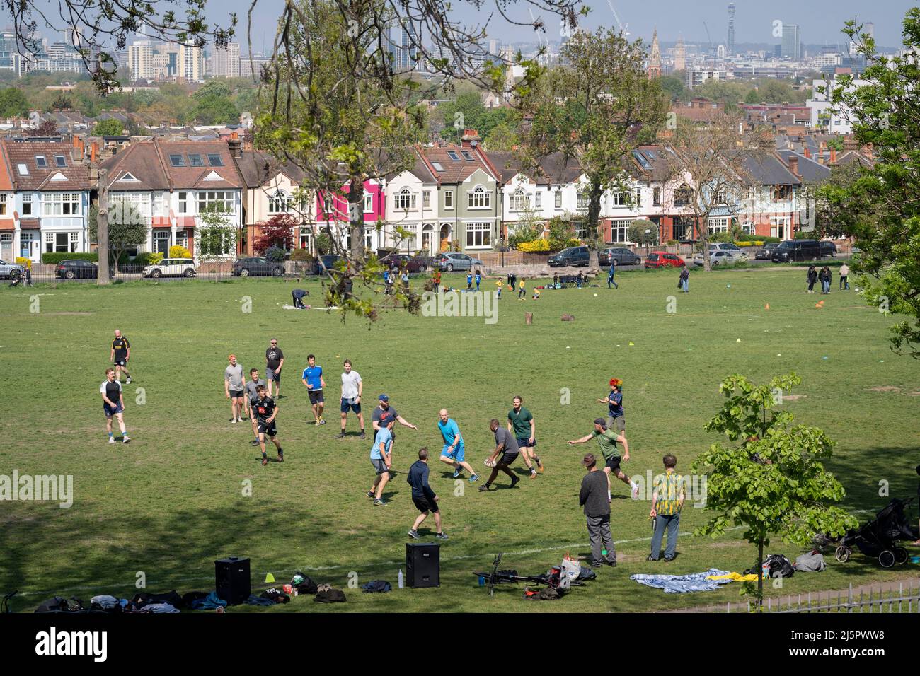 A local game of touch rugby is played in Ruskin Park, a south London green space that overlooks houses in Lambeth, on 24th April 2022, in London, England. Touch rugby is a safer variation of rugby football in which players do not tackle each other but instead touch their opponents using their hands on any part of the body, clothing, or the ball. Stock Photo