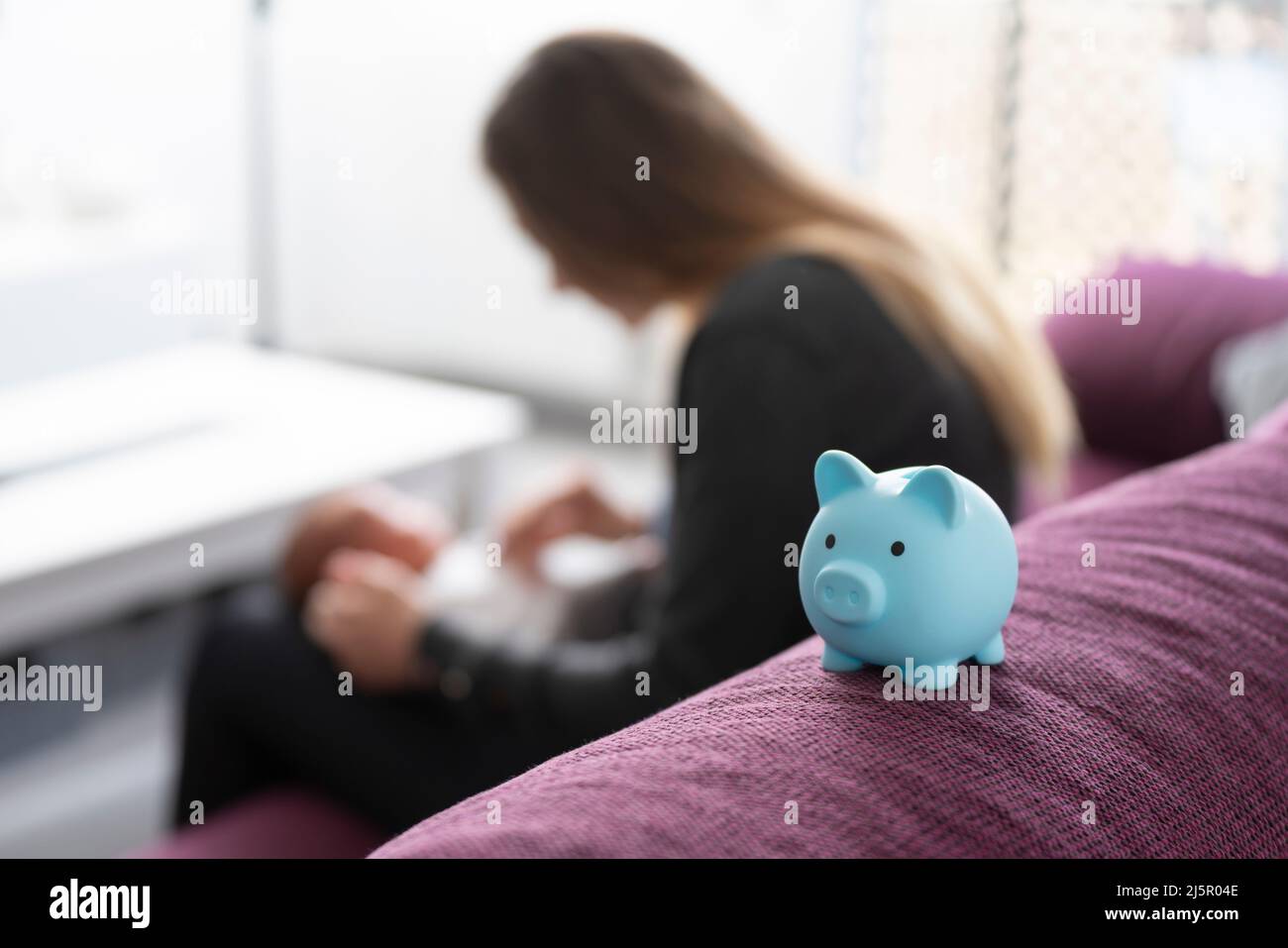 Piggy bank on a sofa with a mother with her baby Stock Photo