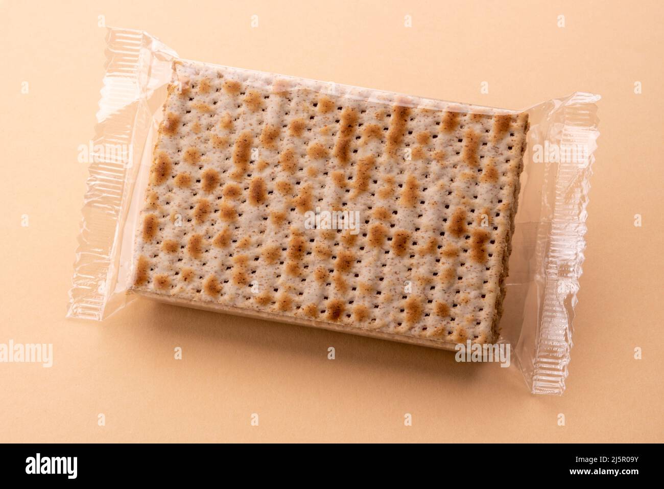 Unleavened matzo in sealed package, bread for Pesach, Jewish holiday of Passover. Matzah flatbreads on light brown background Stock Photo
