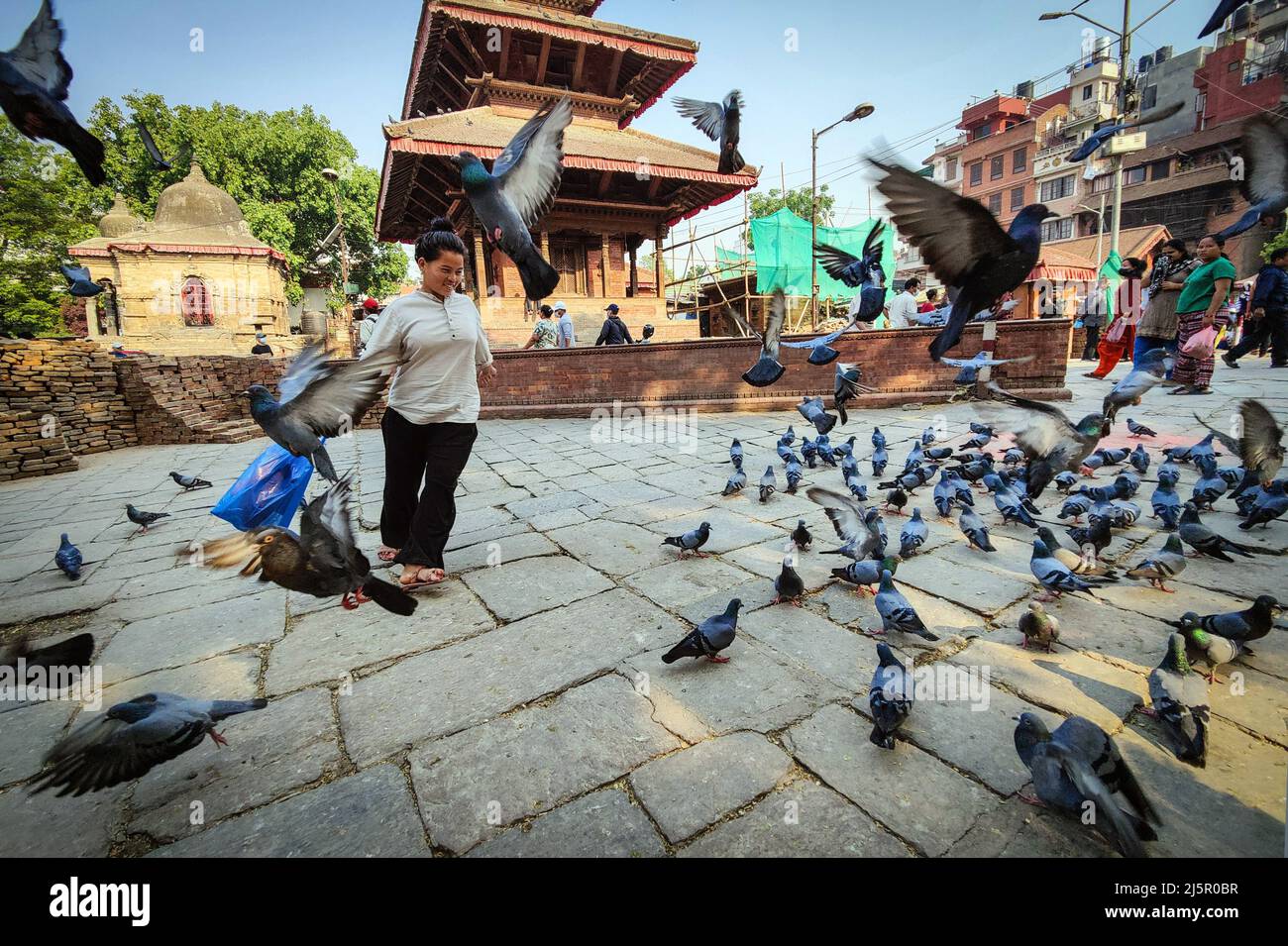 Kathmandu, Bagmati, Nepal. 25th Apr, 2022. A woman enjoys with flying pigeons at reconstruction site of Hanumandhoka Durbar Square in Kathmandu, Nepal on April 25, 2022. Nepal on Monday marked the seventh anniversary of a devastating Gorkha earthquake that killed almost 9,000 people and left millions homeless. (Credit Image: © Sunil Sharma/ZUMA Press Wire) Stock Photo