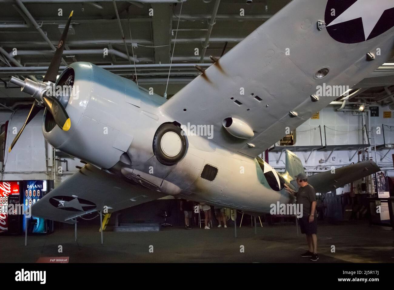 Fighter F4F Wildcat plane contemplated by a visitor at the USS Midway aircraft carrier hangar deck, San Diego Navy Pier Stock Photo